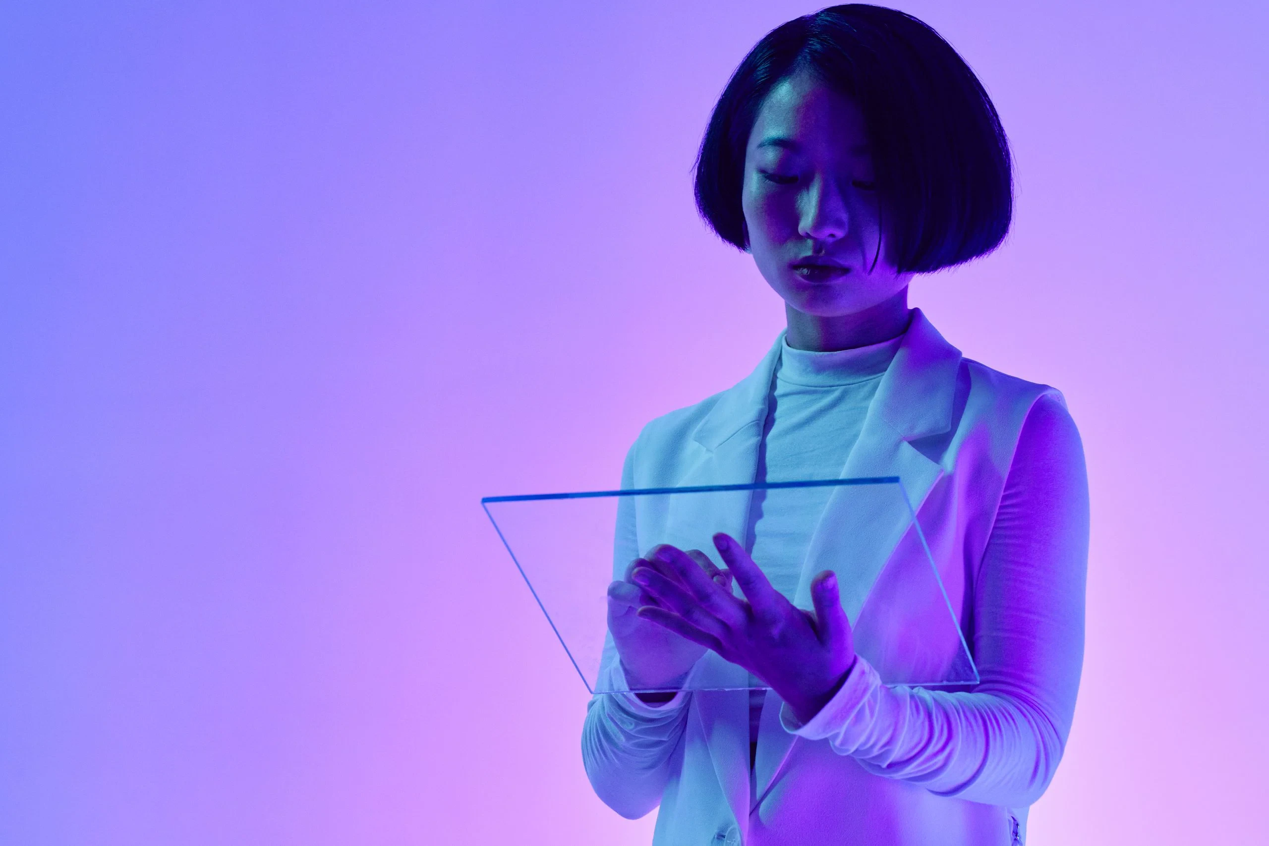 A person holding a transparent screen in purple and blue light, illustrating scrutiny of AI systems and their safeguards.